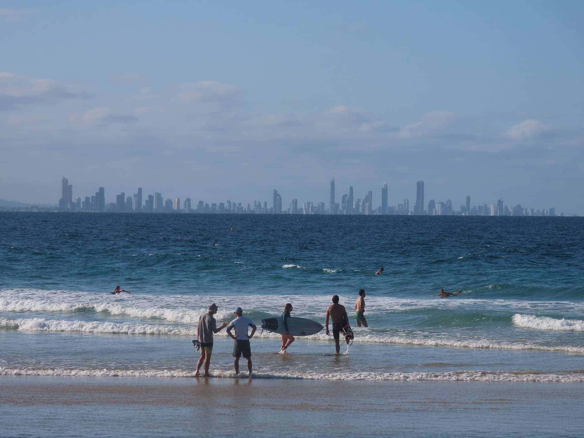 Surfers on Coolangatta beach with the Gold Coast skyline behind them